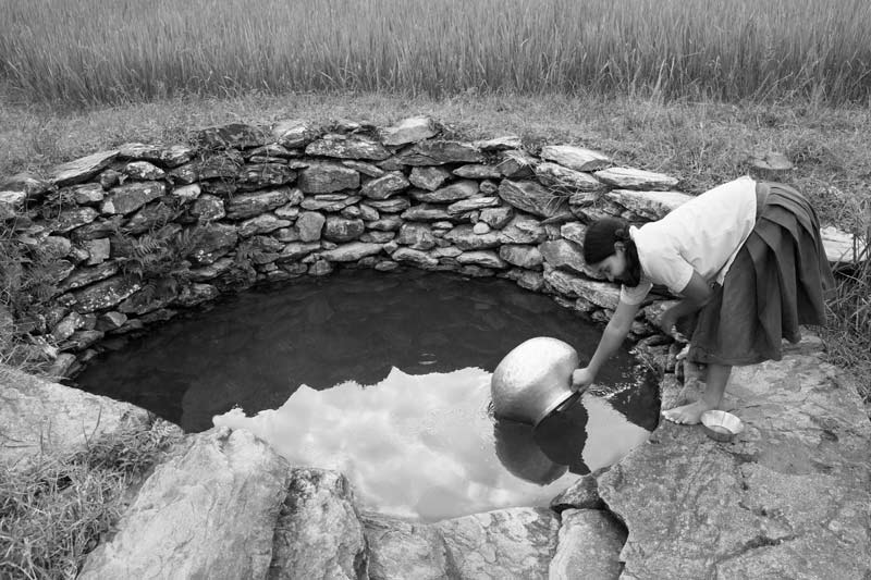 Traditional water supply science and technology of India - Drinking water being fetched from a well located at the base of a valley in a Munda tribal village in West Singhbhum district, Jharkhand